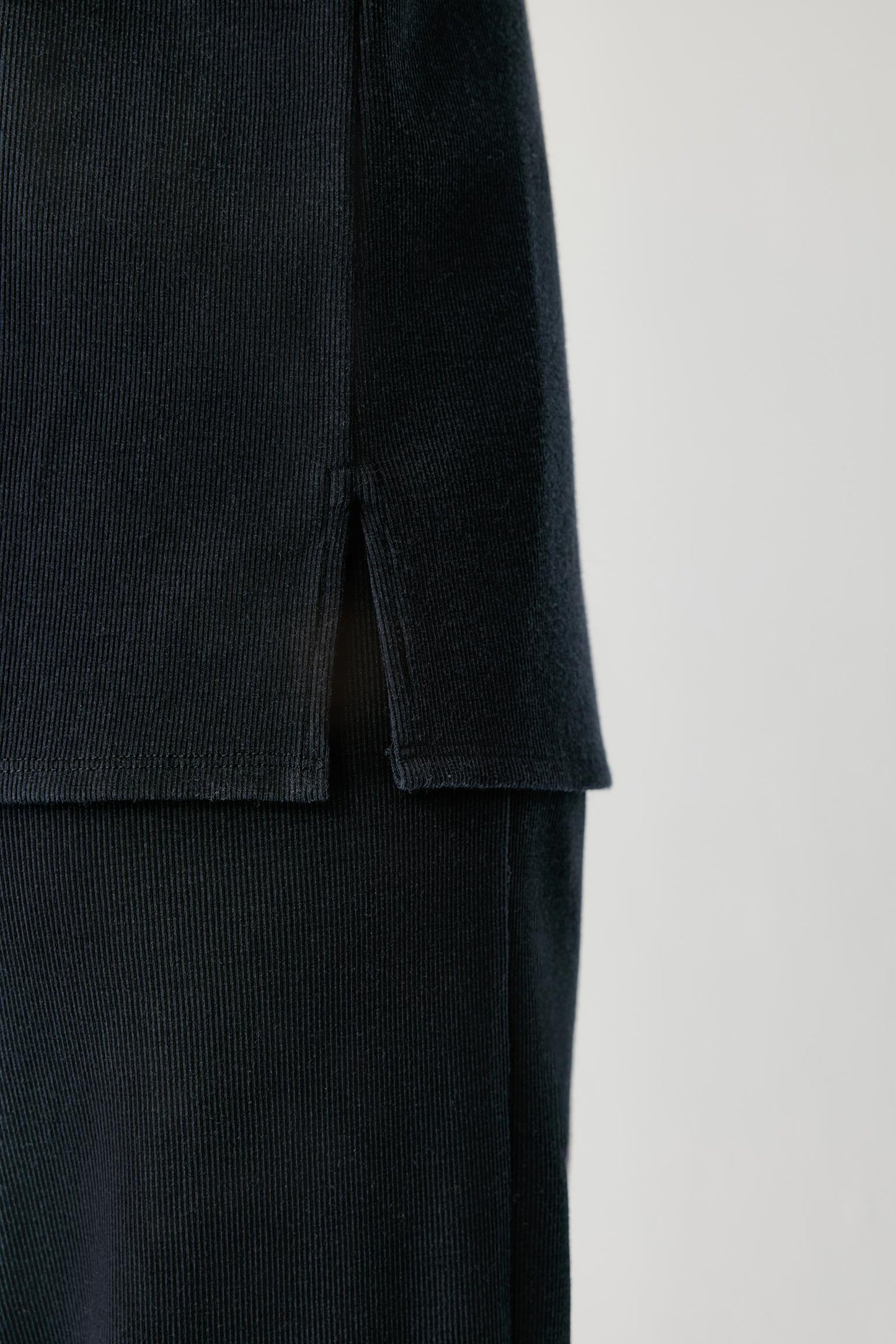 Close-up of the side slit and textured fabric of a navy shirt.