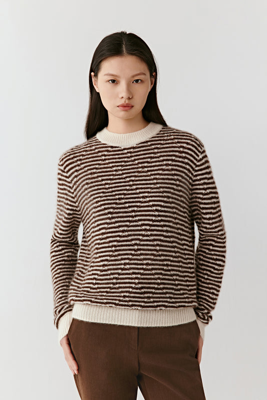 Three-quarter view showing the striped cashmere-silk pullover, emphasizing its relaxed fit, ribbed trims, and subtle natural-toned pattern.