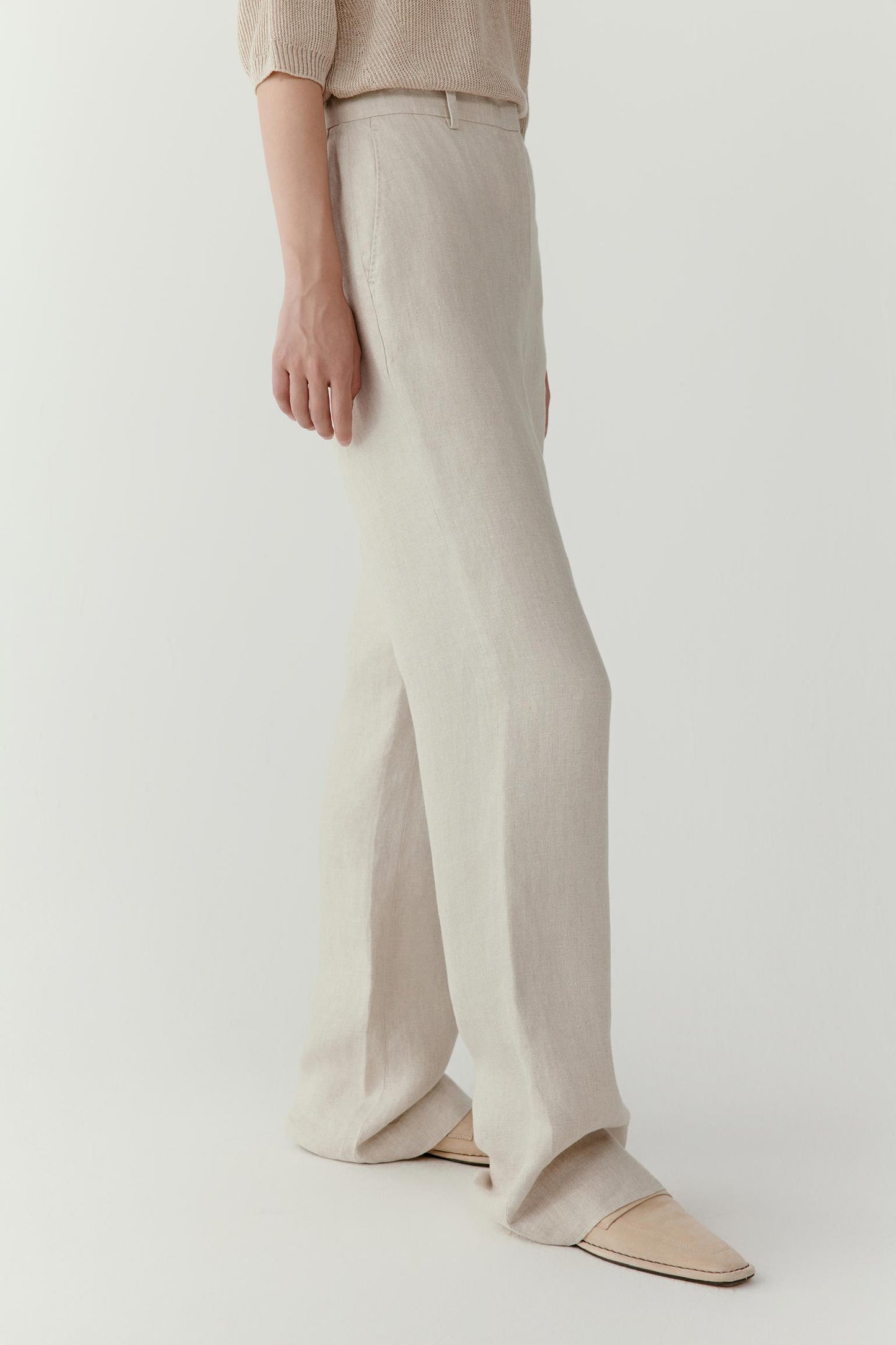 Close-up view of the lower leg and hem area showing the straight cut and clean finishing. The image highlights the fluid drape, lightweight texture and refined silhouette created by the natural linen twill construction.