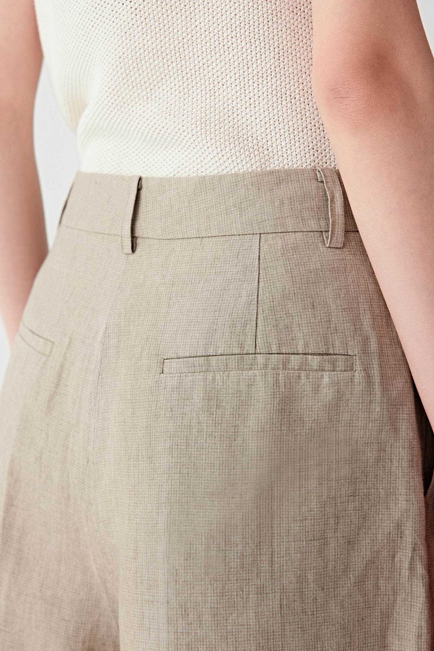 Close-up of pocket and fabric surface showing visible stitching, natural tonal variation and lightly textured linen weave