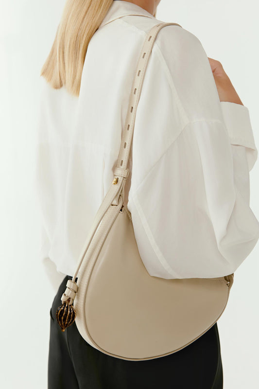 Side view showing the bag resting against the hip. The crescent shape becomes more pronounced, emphasizing the curved profile and minimal construction.