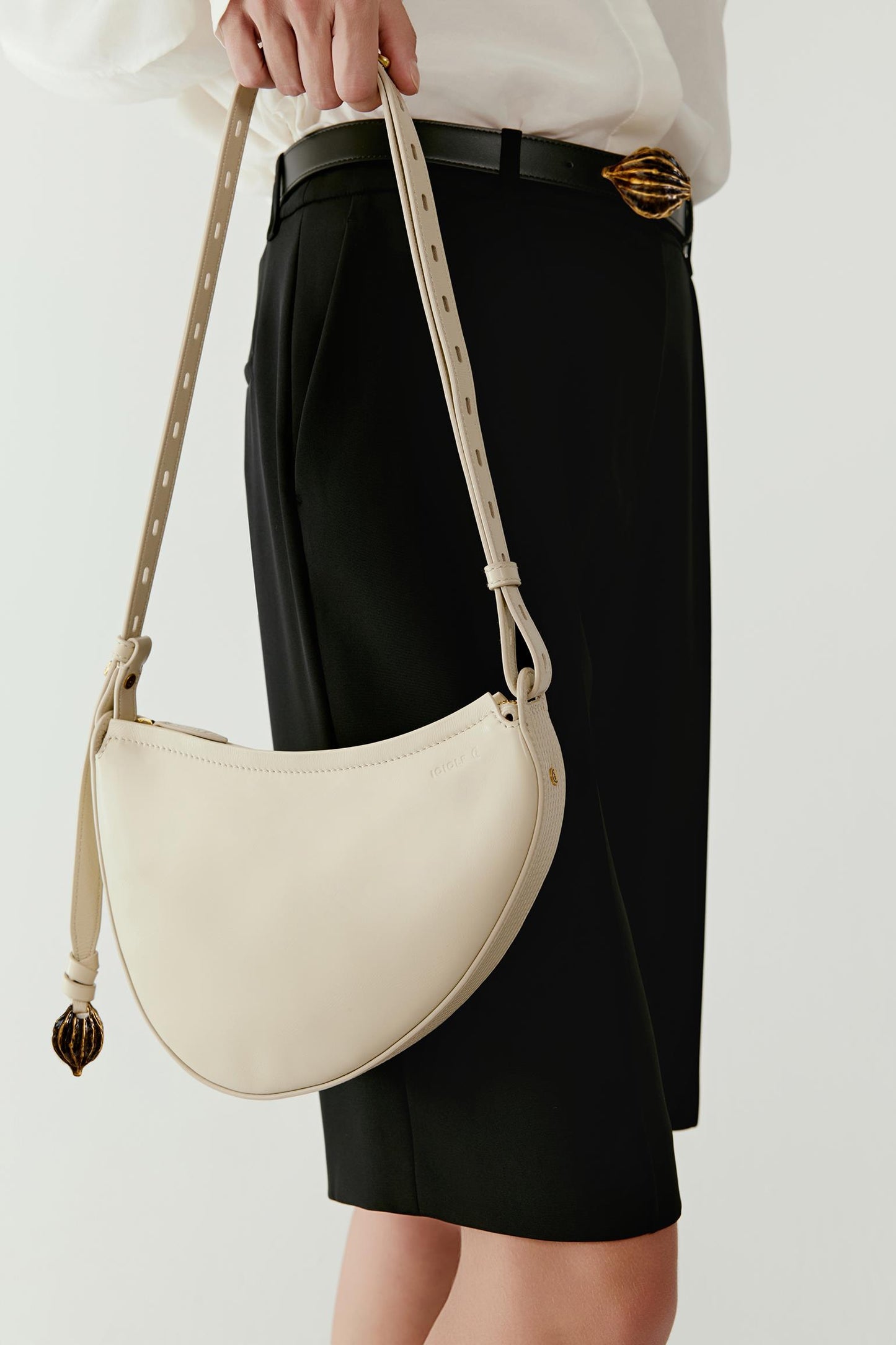 Three-quarter view highlighting the bag worn with a white shirt and dark skirt. The soft leather and subtle gold-toned hardware create a refined contrast against the outfit.