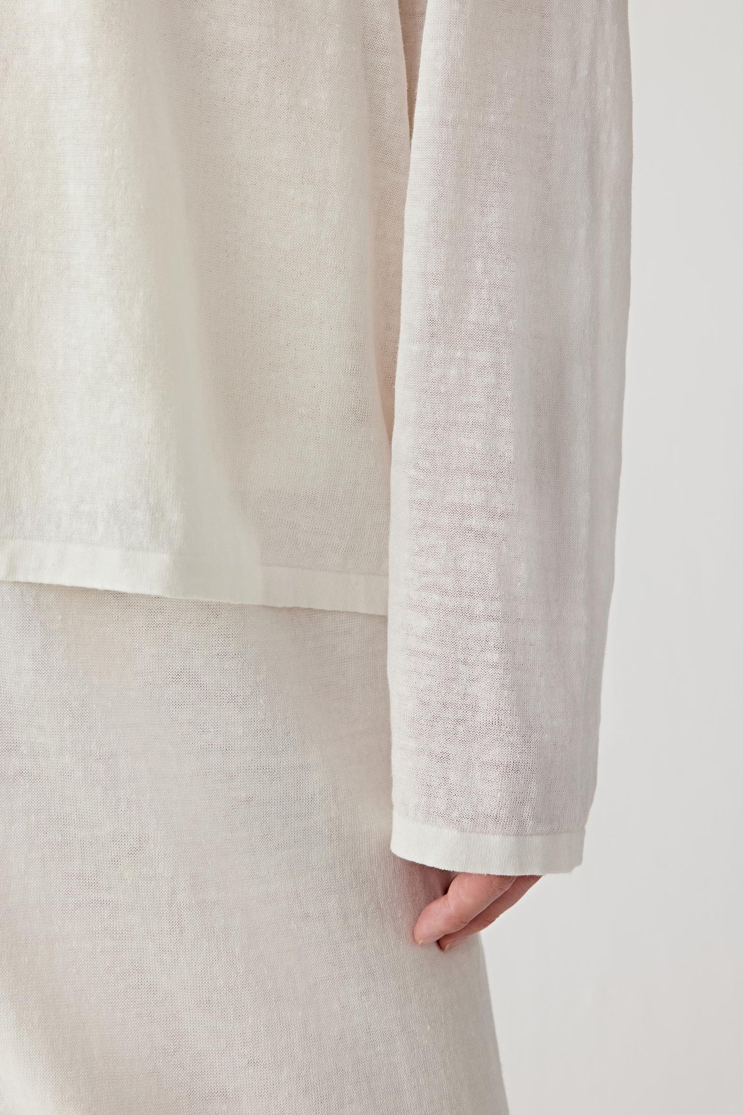 Close-up of sleeve and ribbed trim showing the fine knit construction, ribbed finishing and subtle transparency of the fabric surface