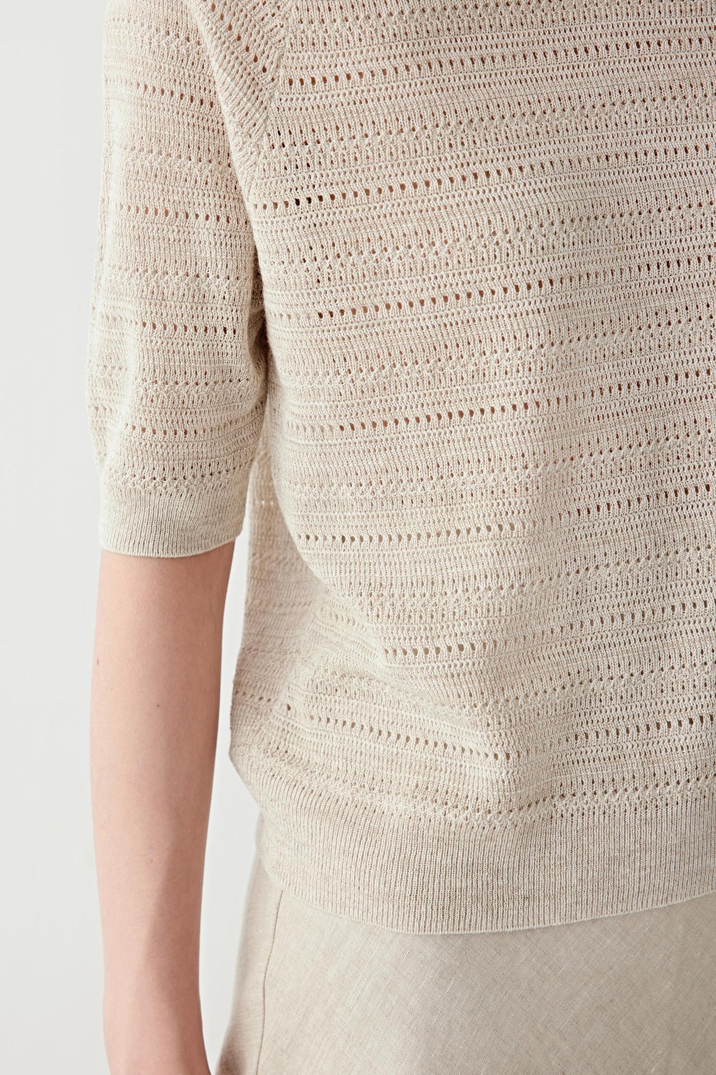 Close-up of sleeve and ribbed trim showing the openwork construction, ribbed finishing and subtle irregularities of the linen and silk yarn blend