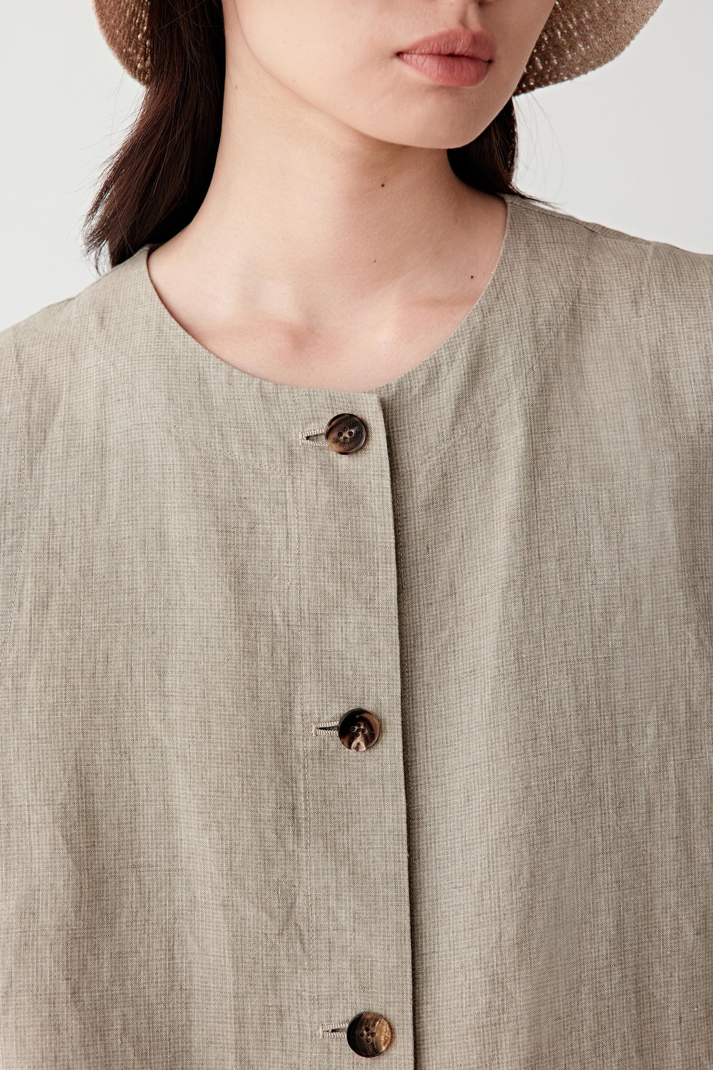 Close-up of front fastening and fabric texture showing the concealed placket, visible stitching and mini check-like woven irregularities characteristic of the linen surface