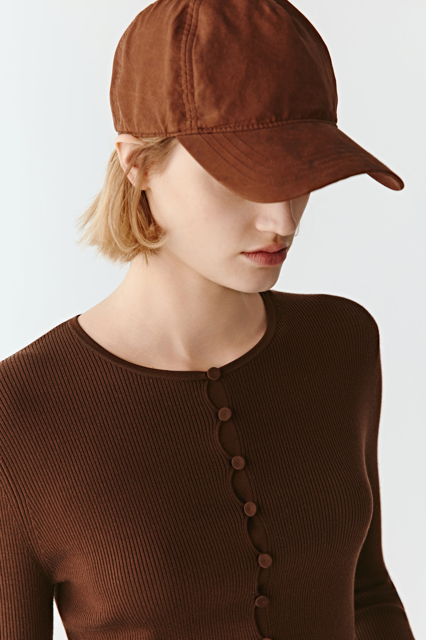 A mid-shot focuses on the covered buttons and minimalist neckline.