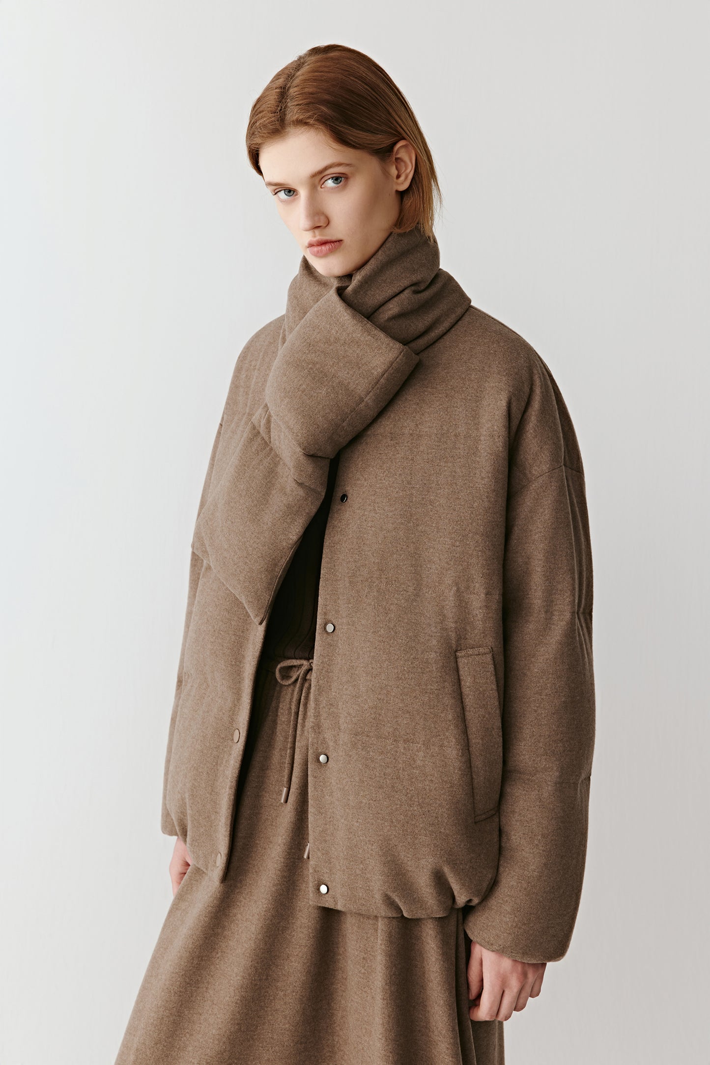 Model in a brown wool and yak down coat with tonal knitwear beneath. The look conveys natural warmth and modern refinement.