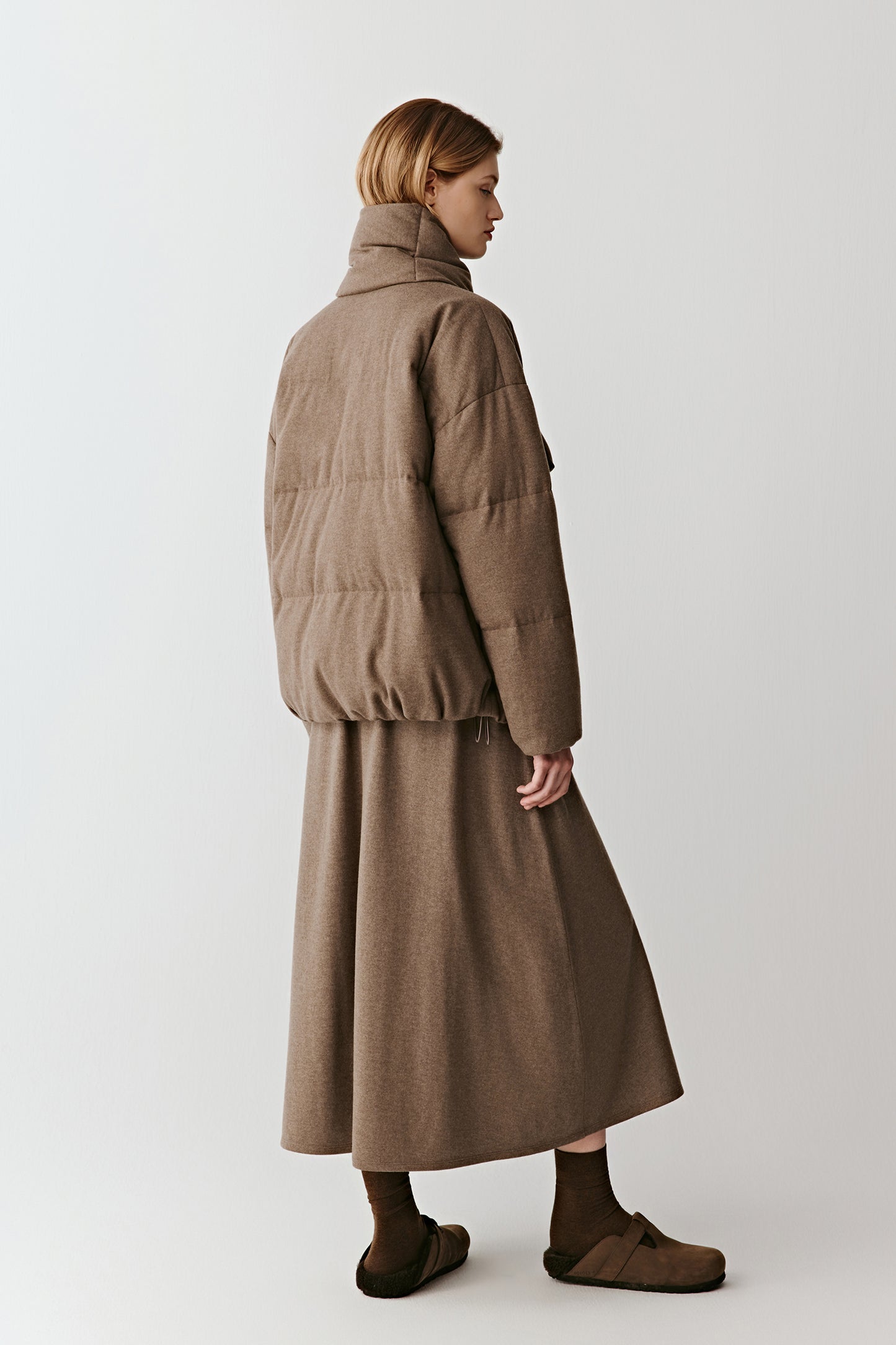 Back view showing the long clean silhouette and fluid movement of the coat.