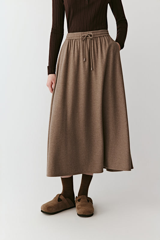 Front view focusing on the long skirt’s clean cut and fluid drape falling just above the ankles.