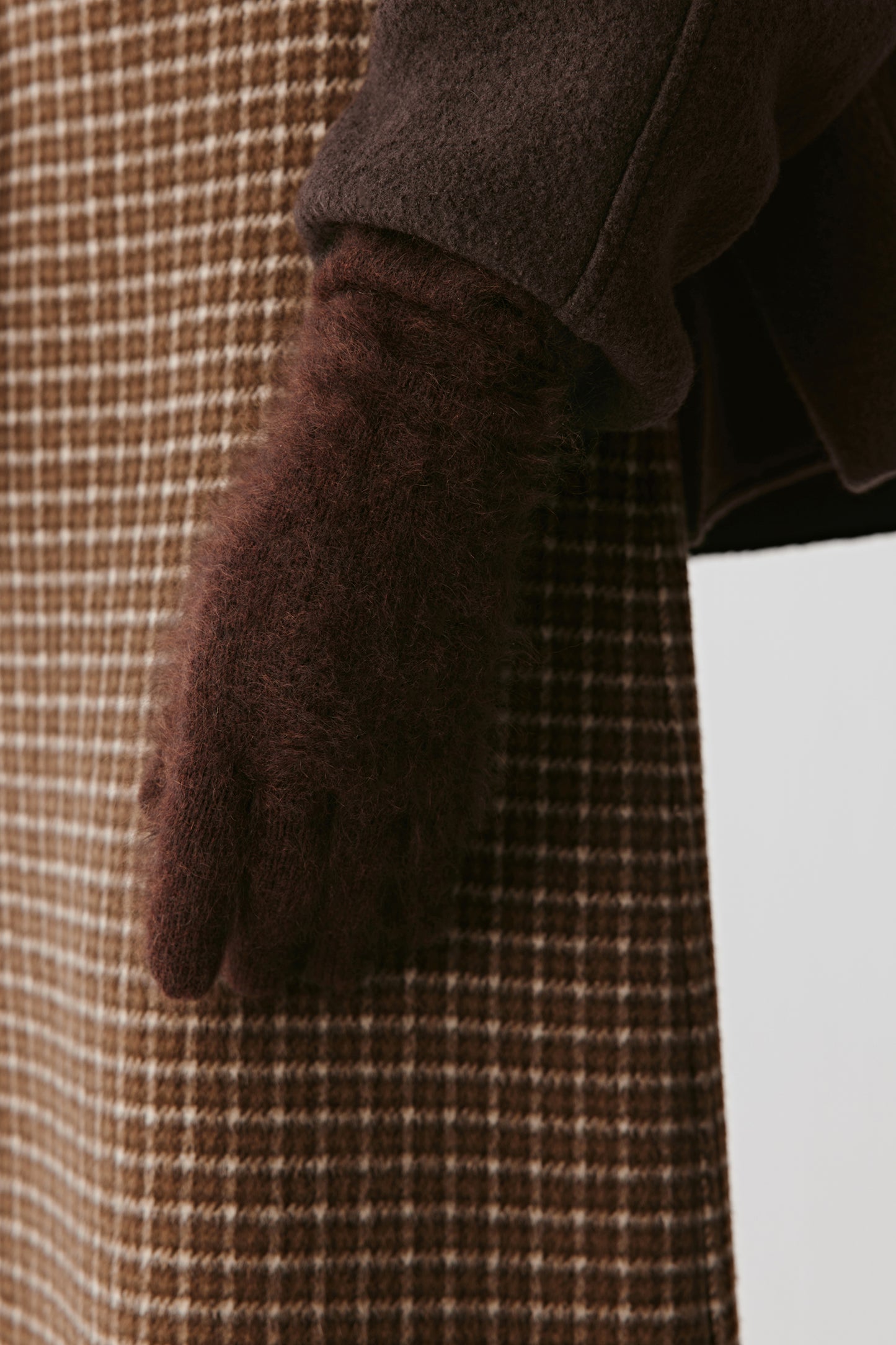 Close-up of brown knit gloves with textured fabric on a light background