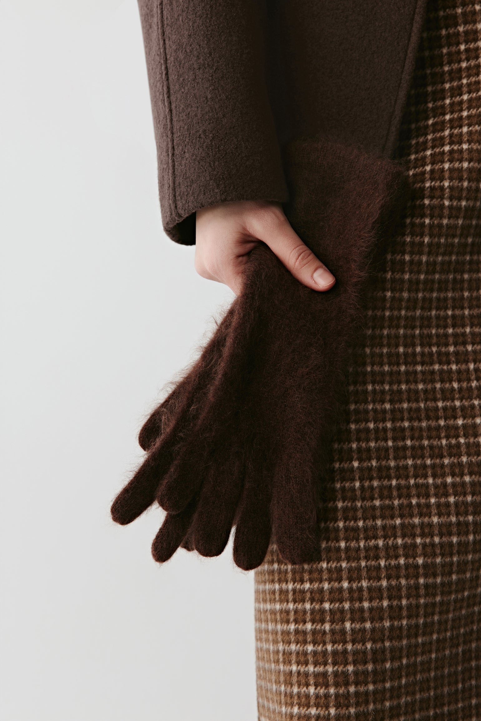 Close-up of brown knit gloves with textured fabric on a light background