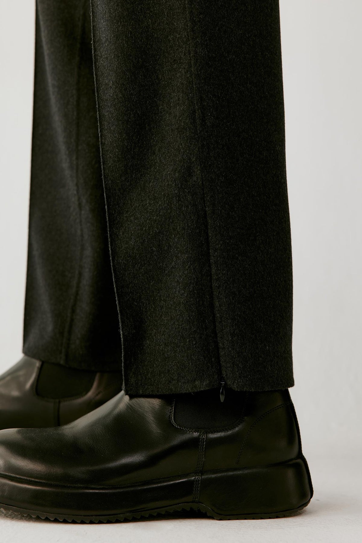 Close-up of the lower leg highlighting the side hem slit and structured double-face wool fabric.