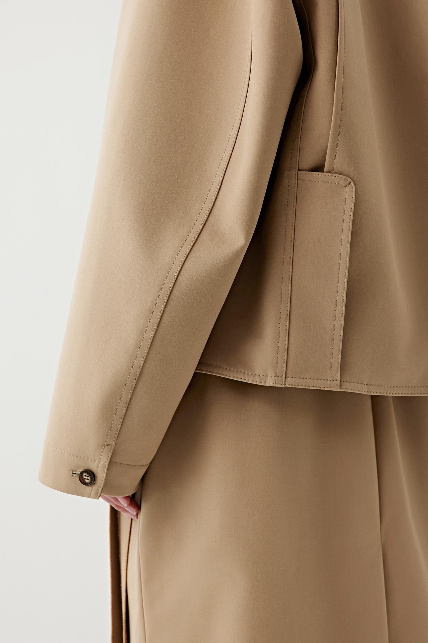 Close-up of the lower coat and sleeve showing the fabric texture, clean seams and fluid structure of the wool-silk blend
