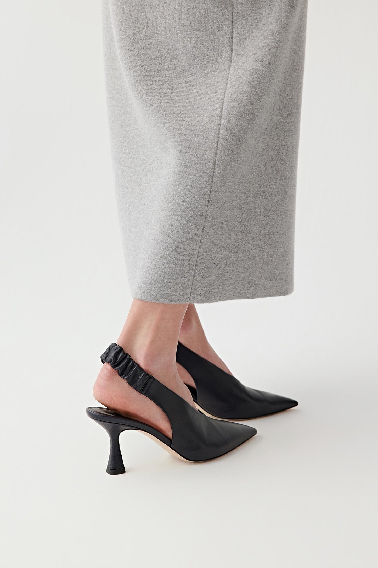 Three-quarter rear view focusing on the back of the shoes, showing the slingback construction, heel shape and the way the strap wraps around the foot while maintaining a secure fit and a clean, structured line