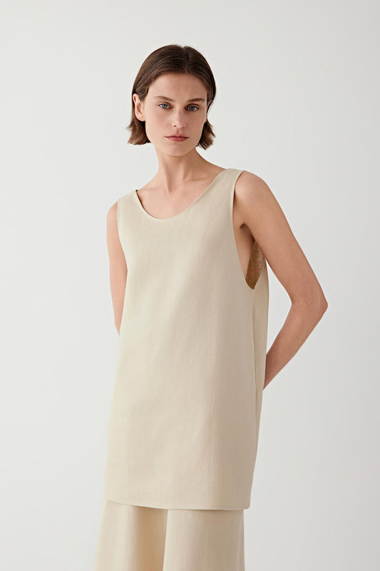 Three-quarter view of the sleeveless cotton-linen blouse showing the clean straight cut, rounded neckline and the fluid drape of the lightweight fabric over the upper body.