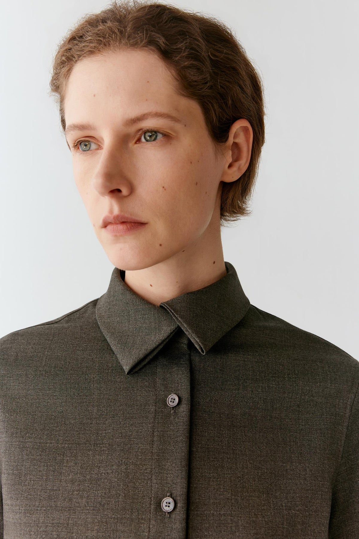 Close-up highlighting the pointed collar, concealed button-front fastening and smooth surface of the wool suiting.