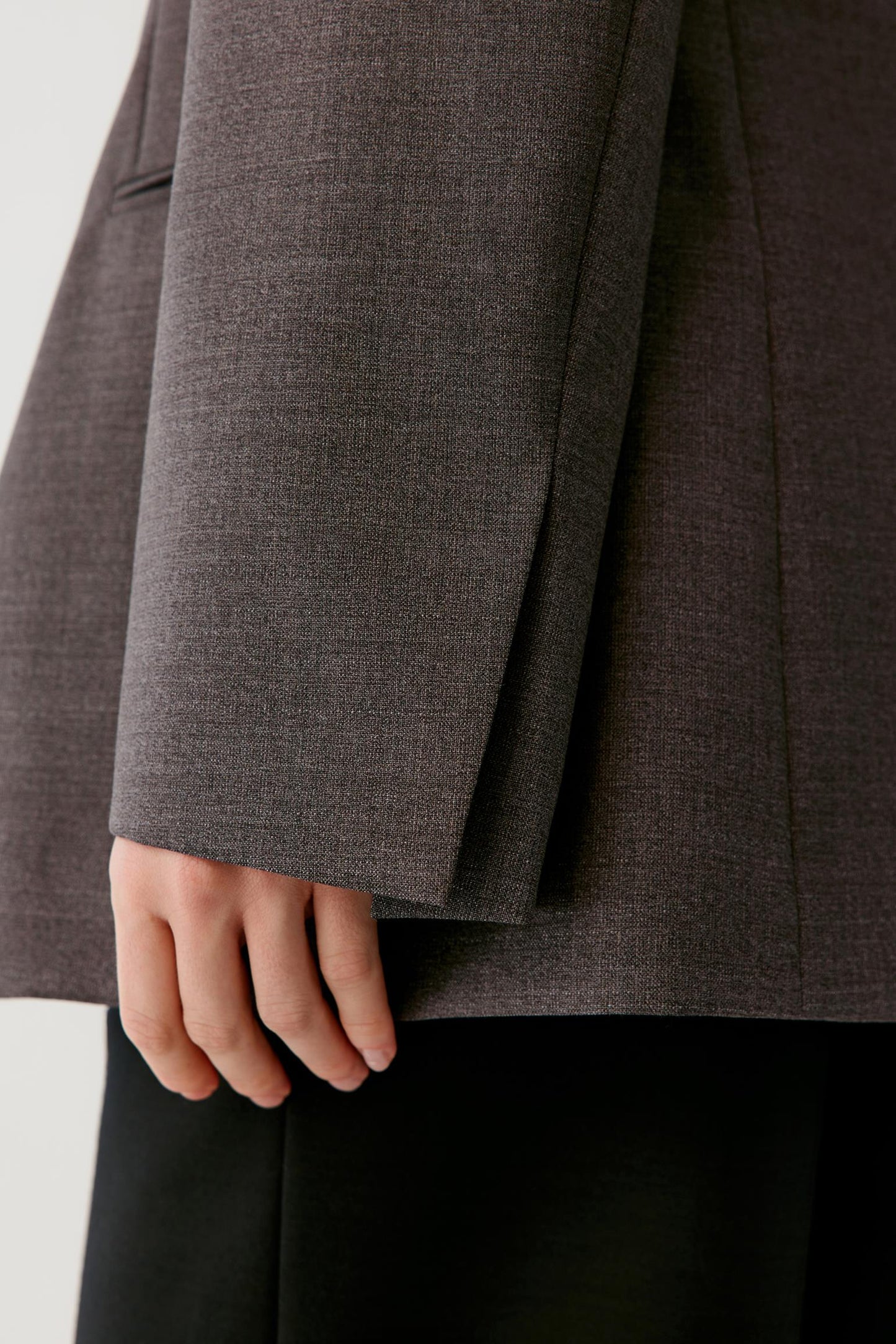 Close-up of the sleeve and cuff, highlighting the clean finish and grey melange wool surface.