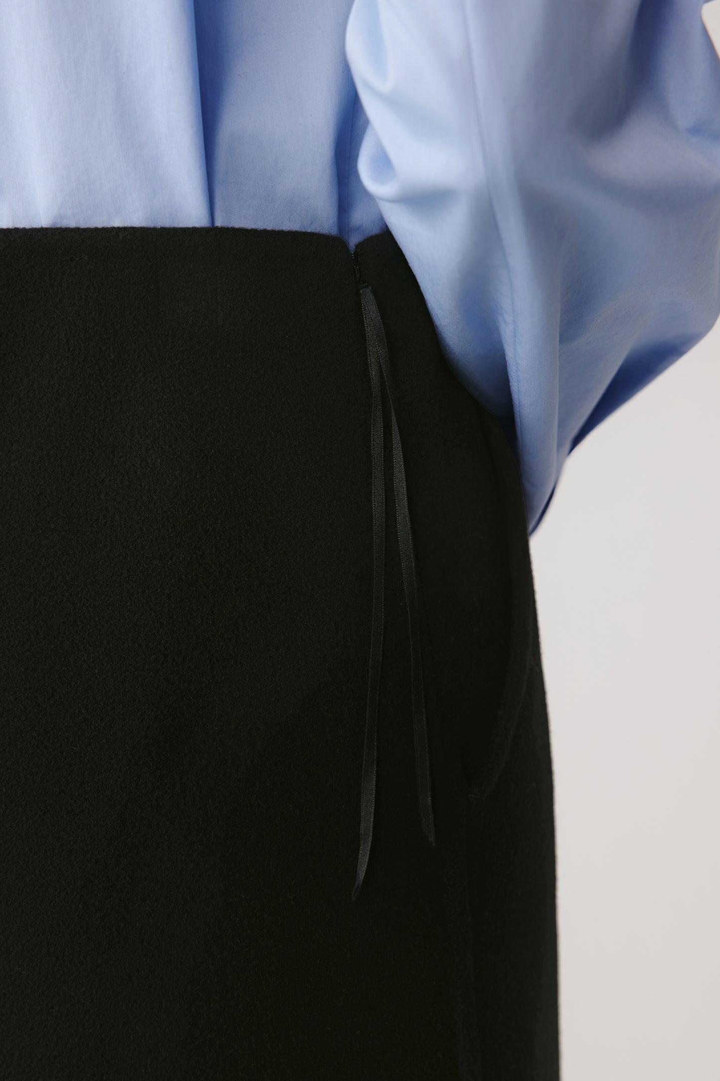 Close-up of the side fastening, topstitching, and inner ribbon, illustrating the garment’s refined tailoring and soft matte finish.