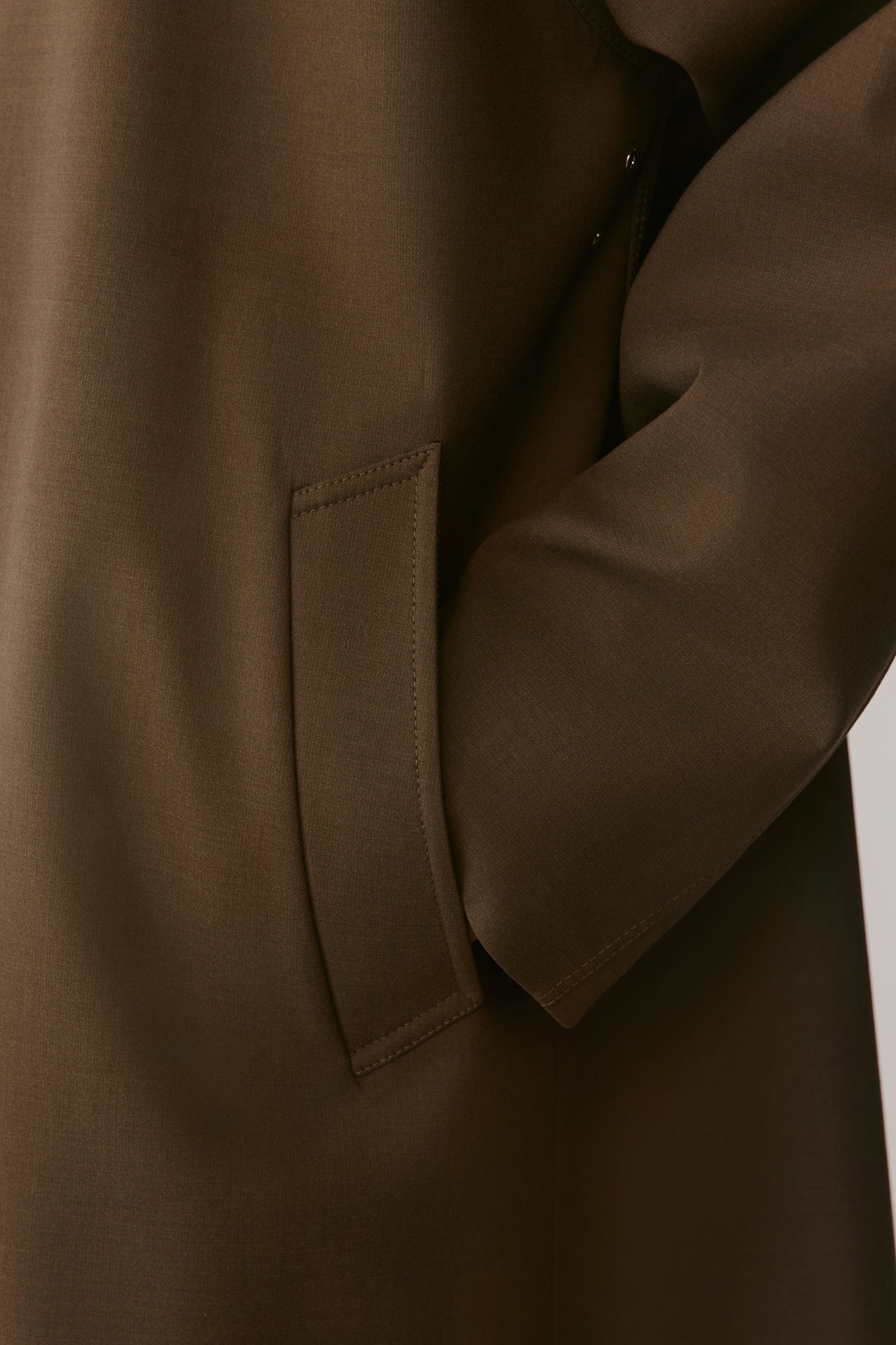 Close-up of the sleeve, showing the tonal stitching and refined texture of the DEW fabric.