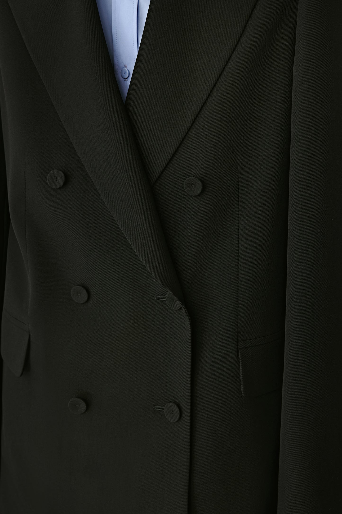 Close-up of the double-breasted front, displaying the matte buttons and refined fabric texture.