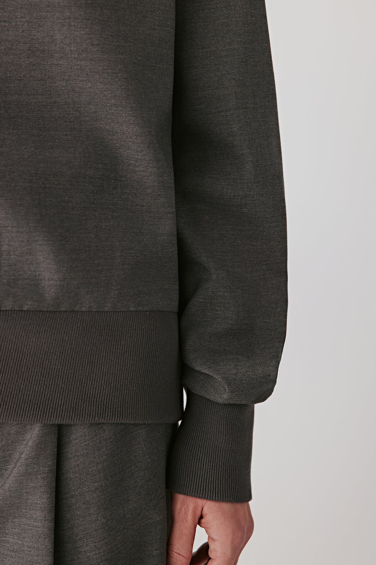 Detail view of the grey wool sateen blouse showing the ribbed cuffs and waistband, highlighting the smooth texture and tailored finish.