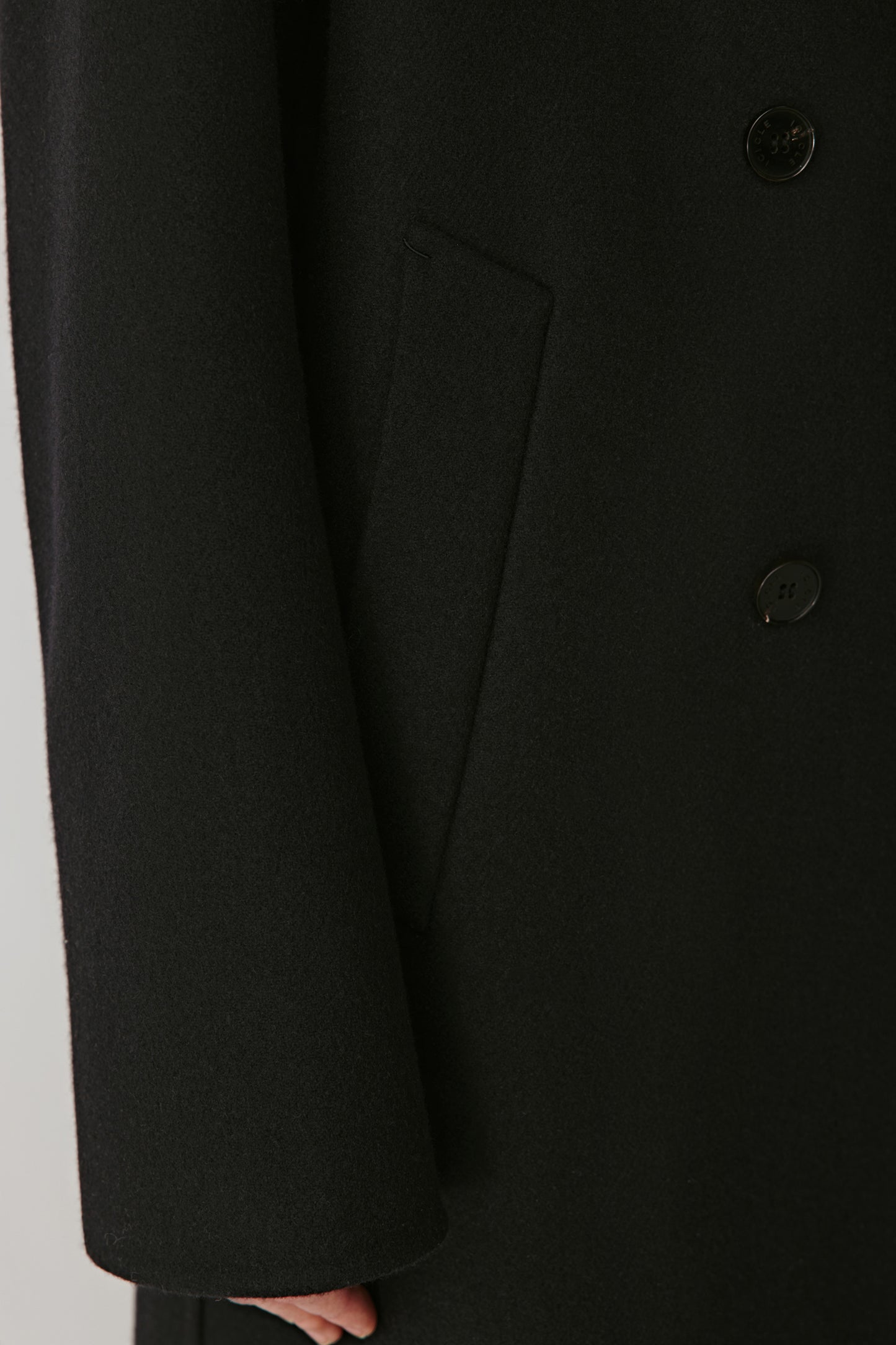 Detail shot of the front flap pocket and buttons, emphasizing fine finishing and material quality.