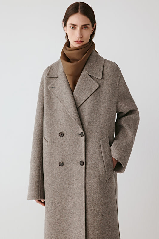 Three-quarter view of the wool coat, revealing the tailored shoulders and clean lines.