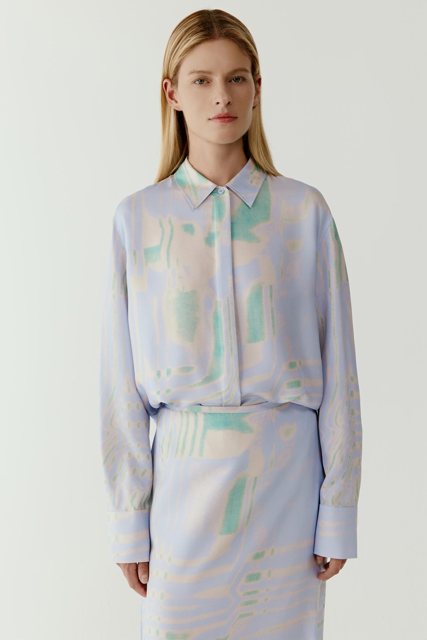 Mid-length front view highlighting the buttoned front, classic collar and the subtle variations in the water-inspired print