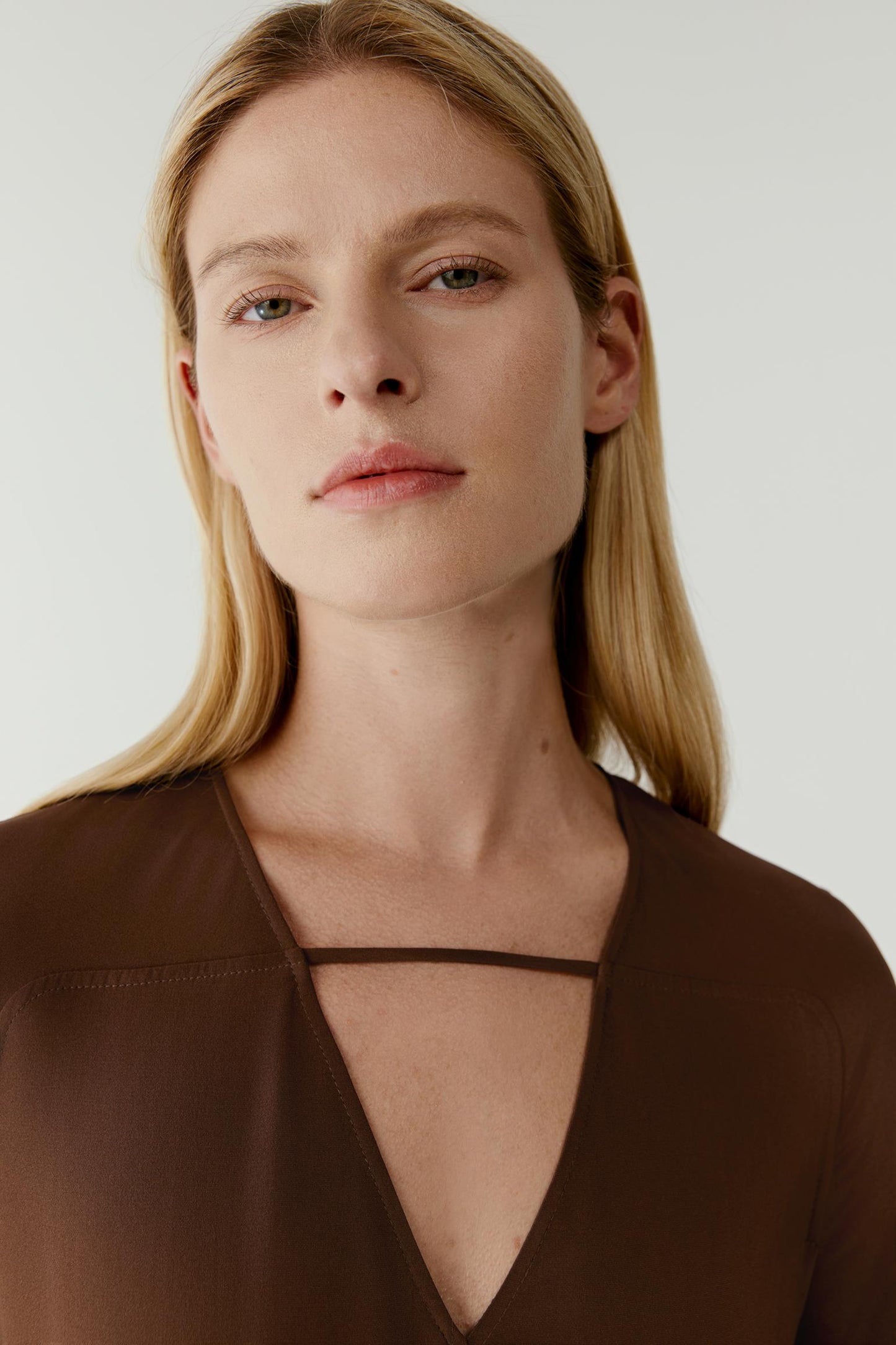Close-up portrait focusing on the neckline, V-shape opening and smooth, softly matte texture of the silk crepete texture of the silk crepe