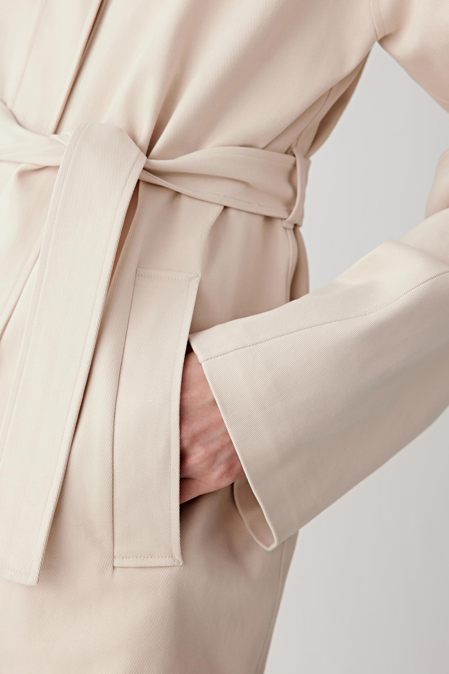 Close-up of sleeve and belt showing stitching, fabric density and structured texture