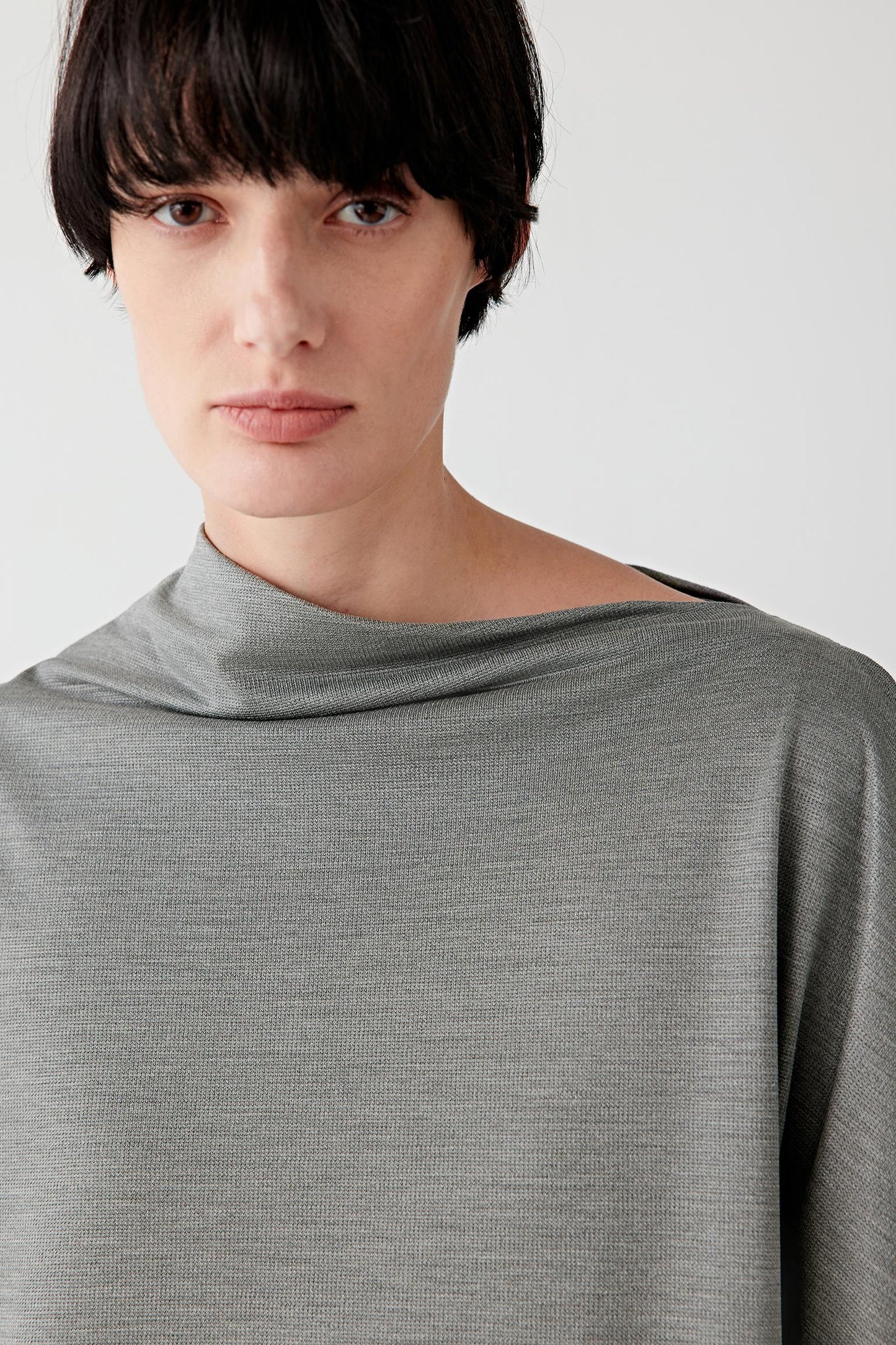 Close-up of fabric and seam detailing showing the fine jersey structure, matte surface and fluid stretch quality of the spun silk blend. The image highlights the softness of the material and the continuous movement created by the asymmetrical construction.