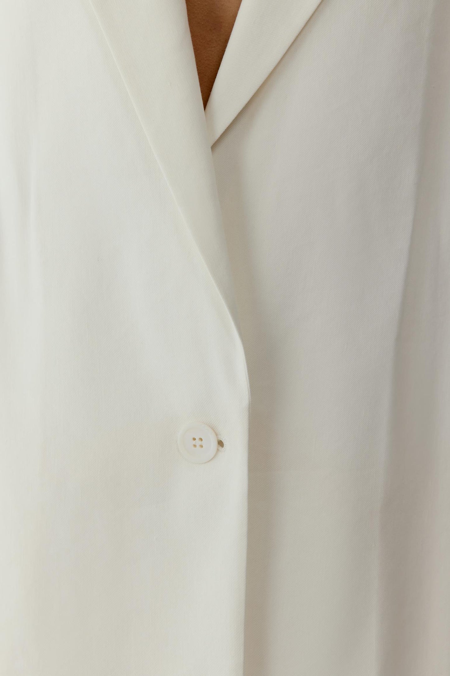 Close-up of the front detailing showing the smooth linen texture, clean edges and refined finishing along the neckline and opening