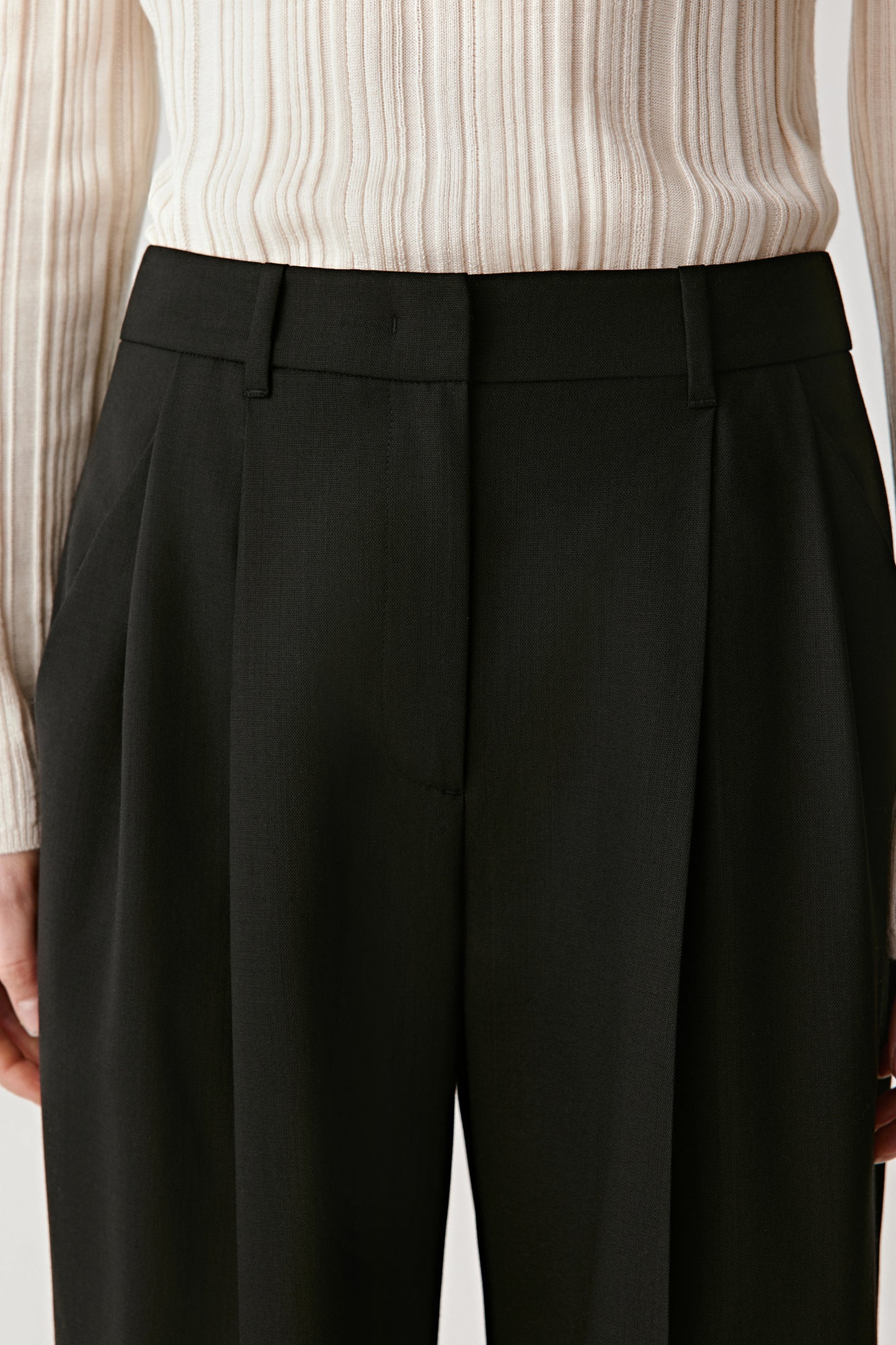 Close-up of the waistband and pleat structure emphasizing precision tailoring.