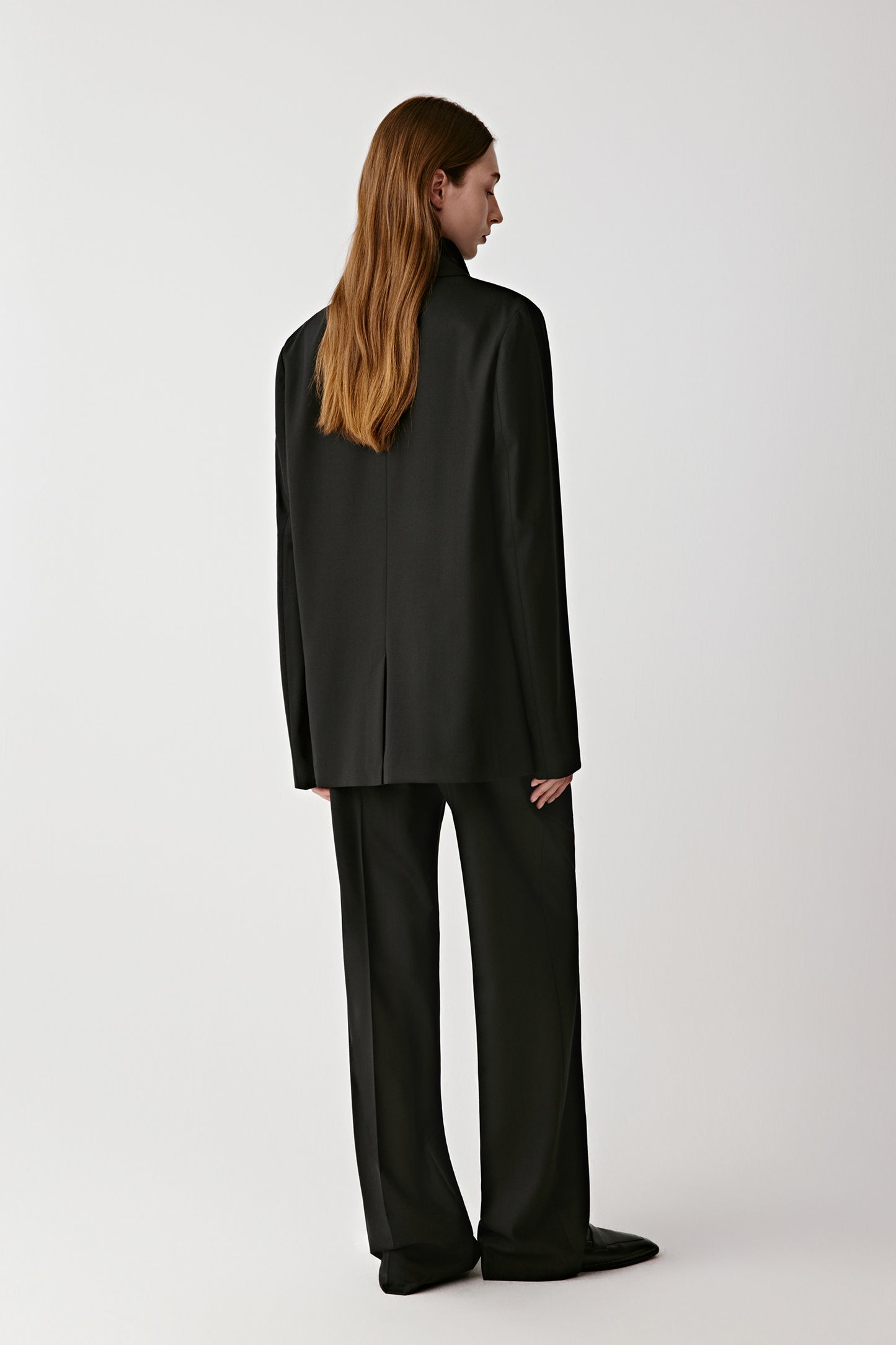 Rear view showing the fluid structure and long lapel line.