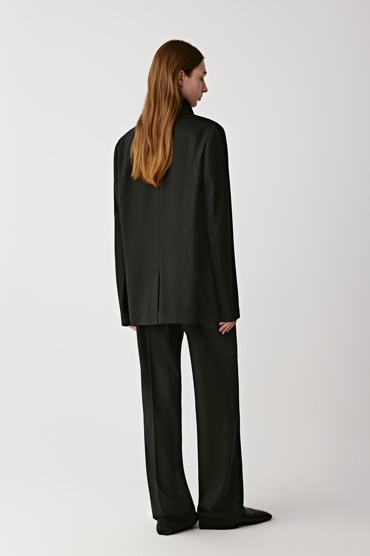 Rear view showing the fluid structure and long lapel line.