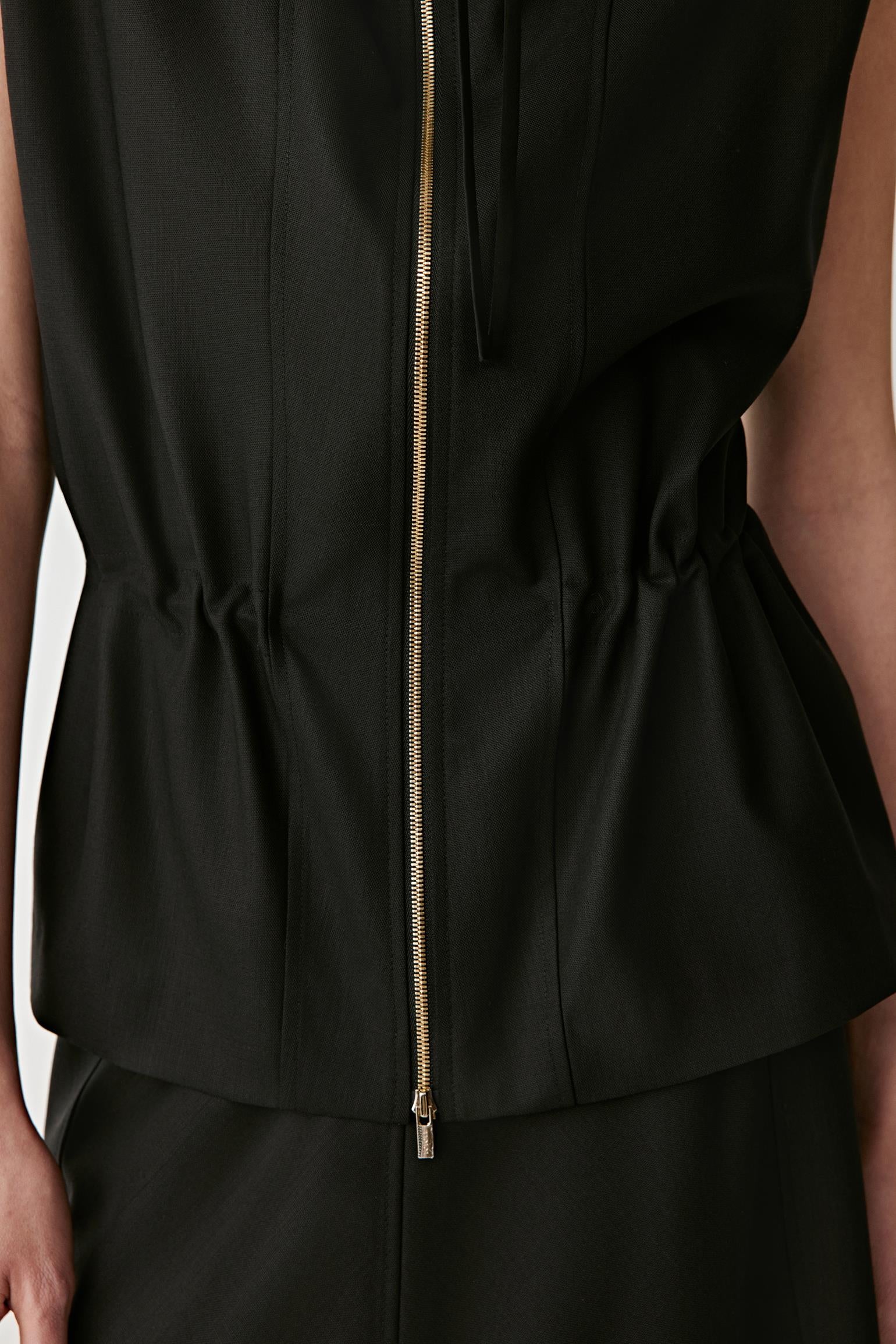 Close-up of the zip fastening, fitted cut and subtle texture of the fabric.