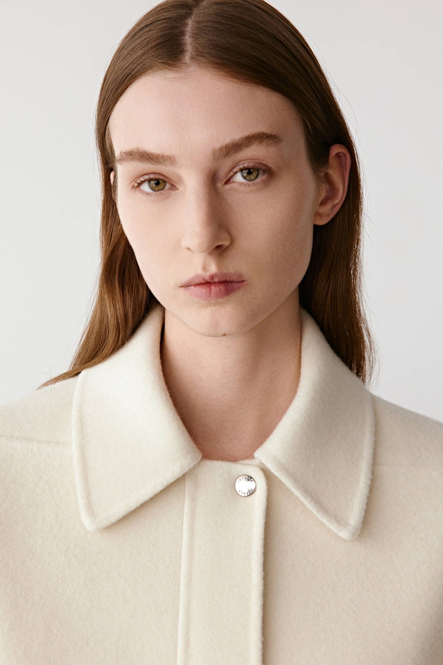 Portrait showing the high collar and serene expression of the look.