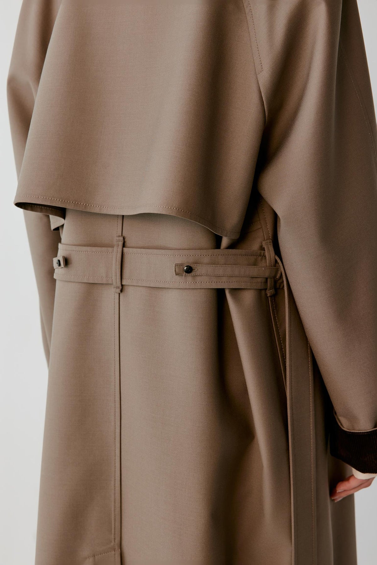 Close-up highlighting the side seam pocket, adjustable back belt and smooth wool and silk surface.