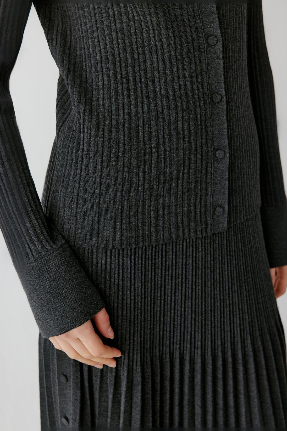 Close-up highlighting the long sleeve, ribbed cuff and fine knit texture of the dark grey cardigan.