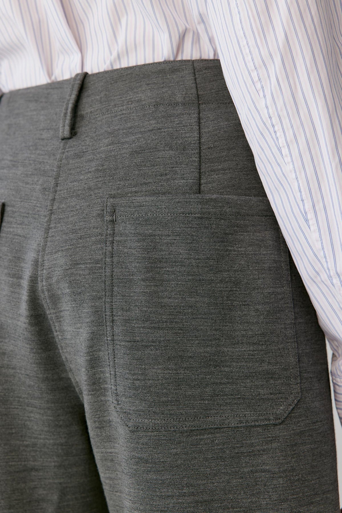 Close-up of the back of the grey melange wool trousers, showing the patch pocket and structured surface.