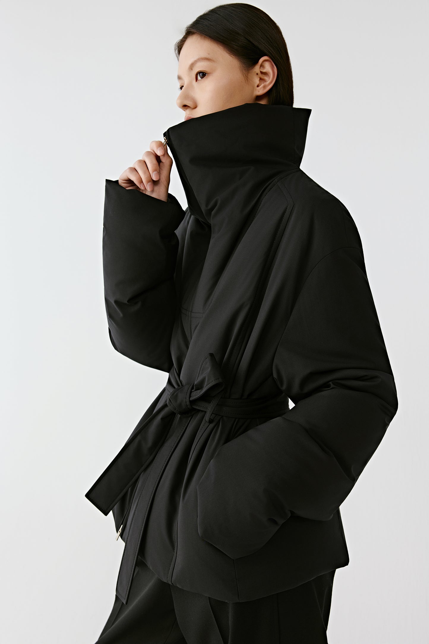 Side view of the blouson highlighting its wrap-style belt and relaxed fit.