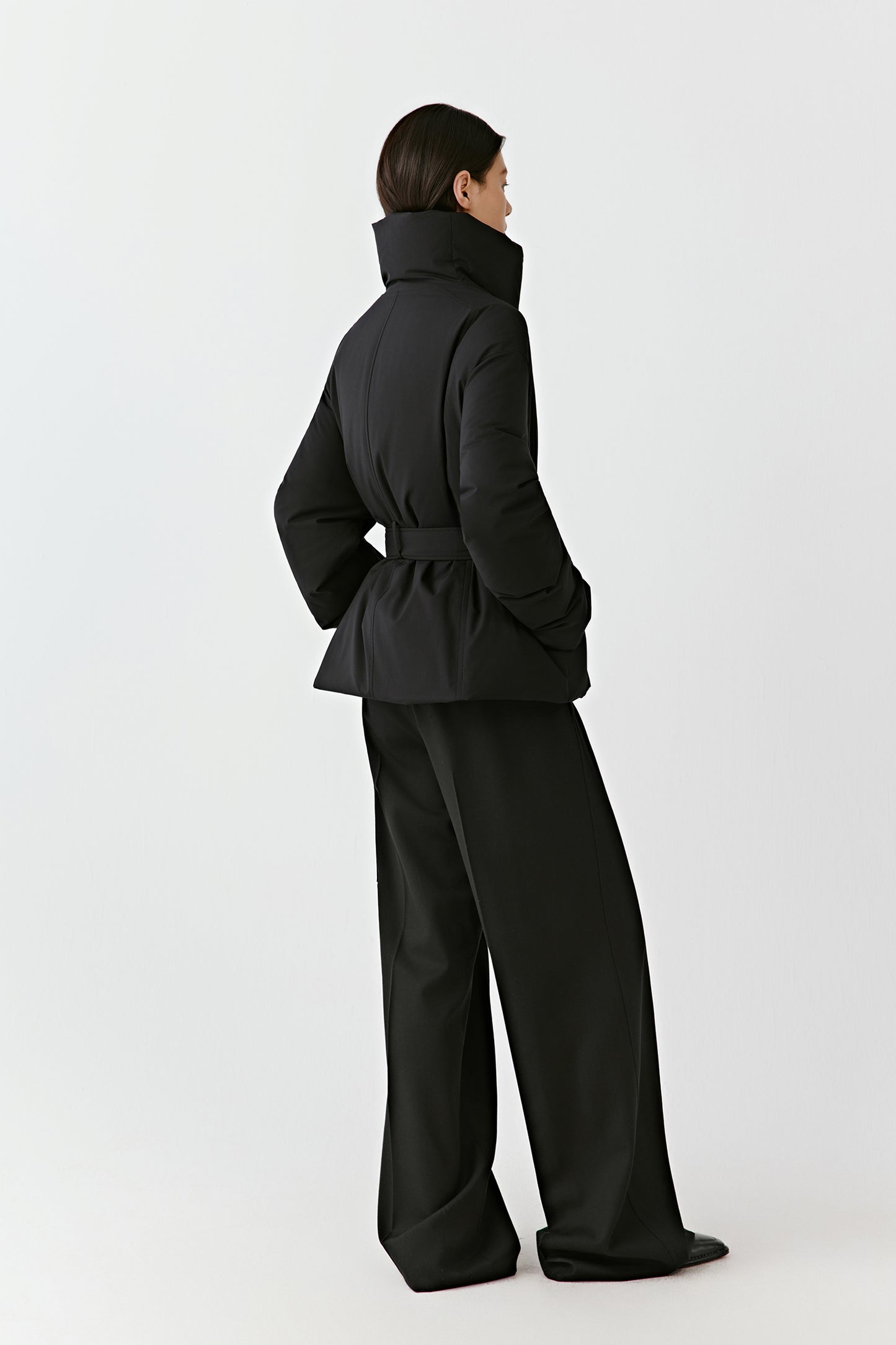 Back view showing the long draped silhouette and soft structure of the jacket.