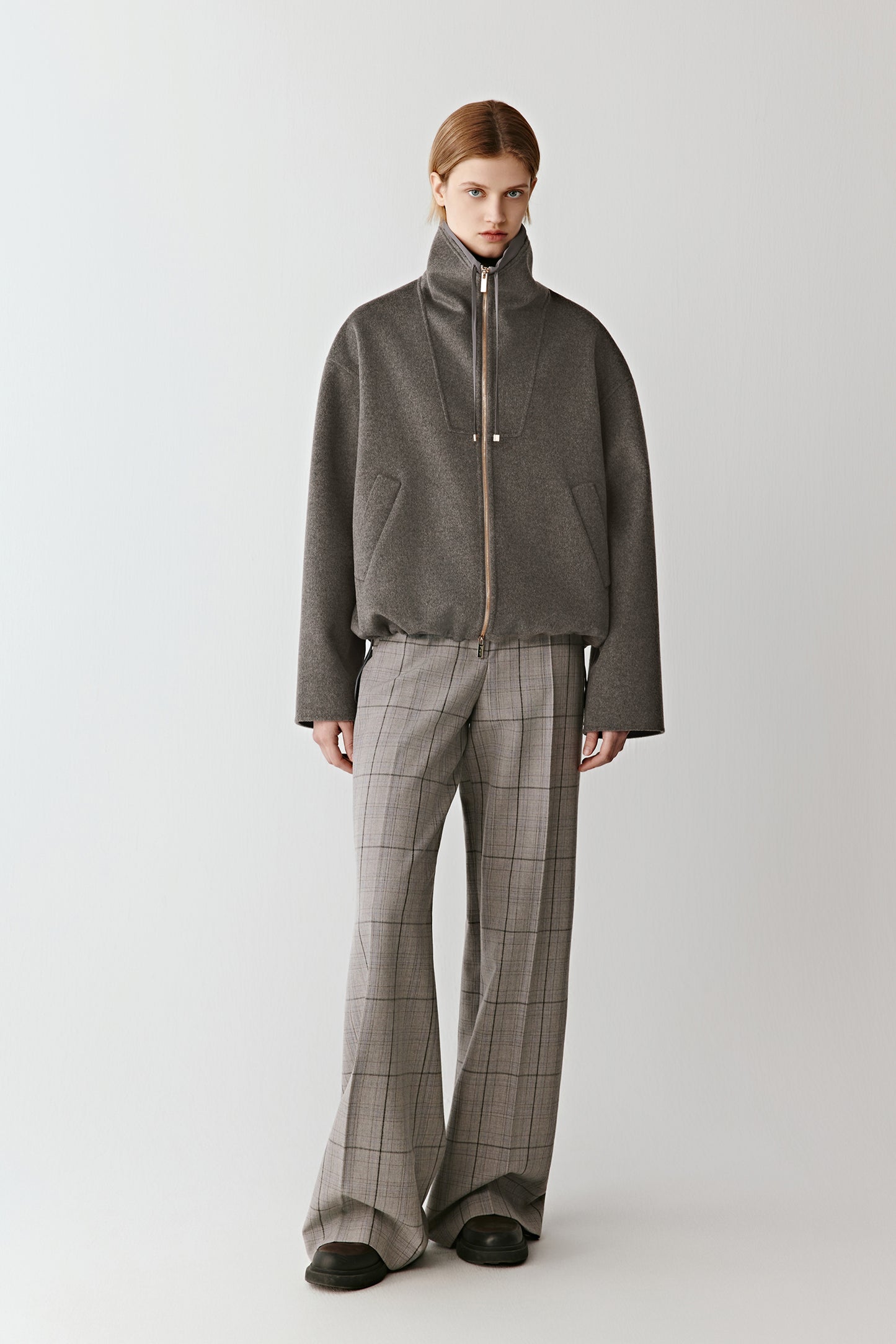 Front view of a model wearing a grey double-faced wool and silk zip jacket with a relaxed fit and minimal lines.