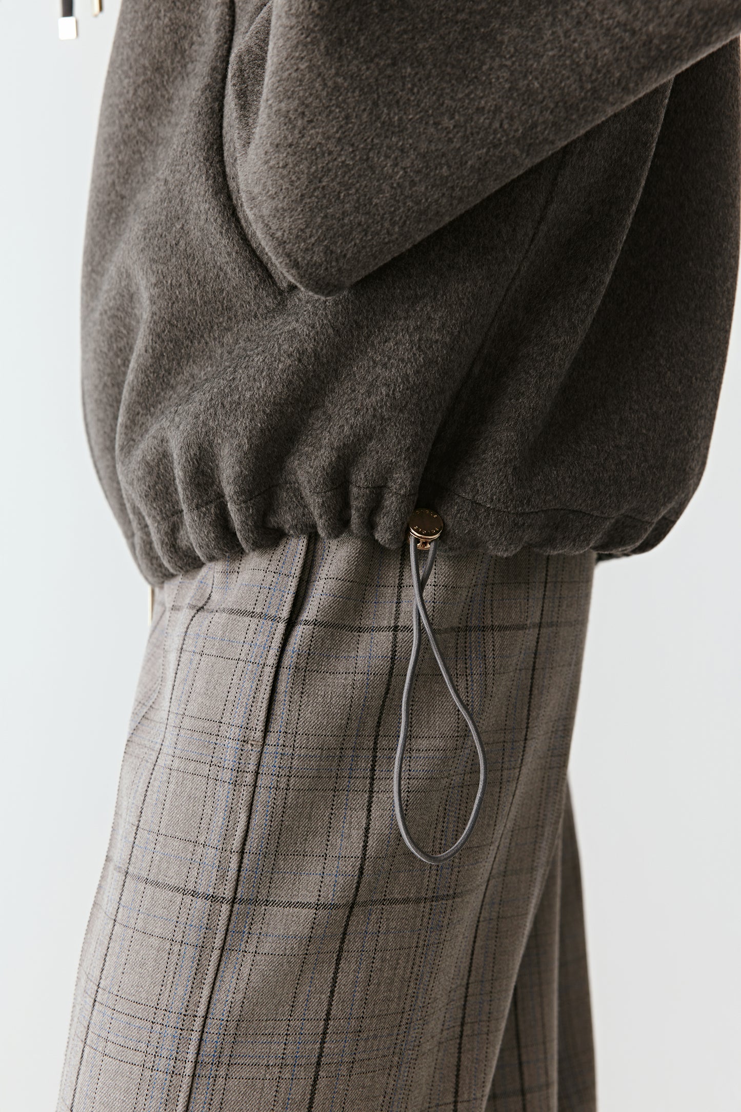 Close-up focusing on the collar drawcords and double-faced texture in grey wool and silk.
