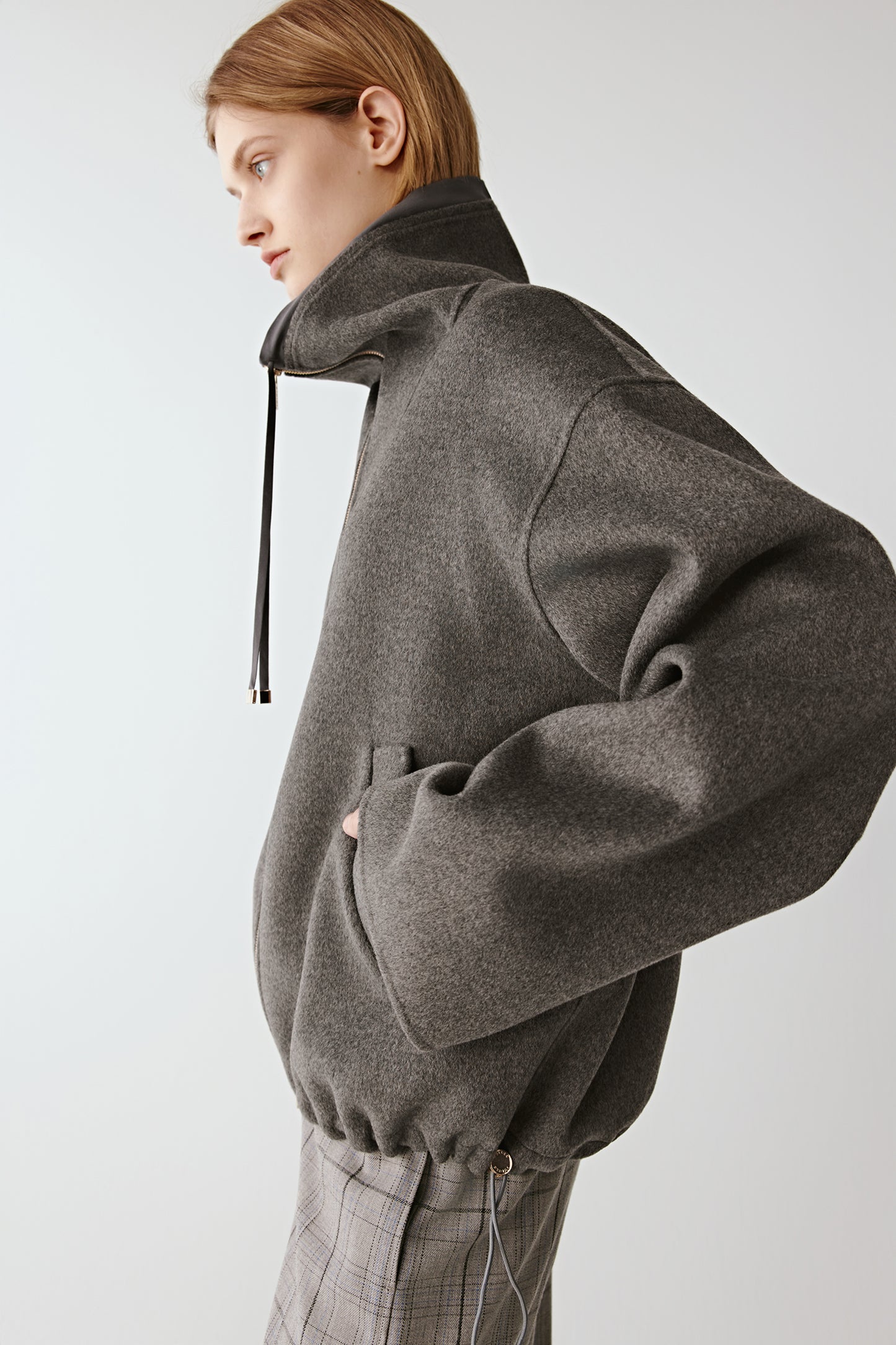 Profile view of the model highlighting the slanted pockets and zip fastening.