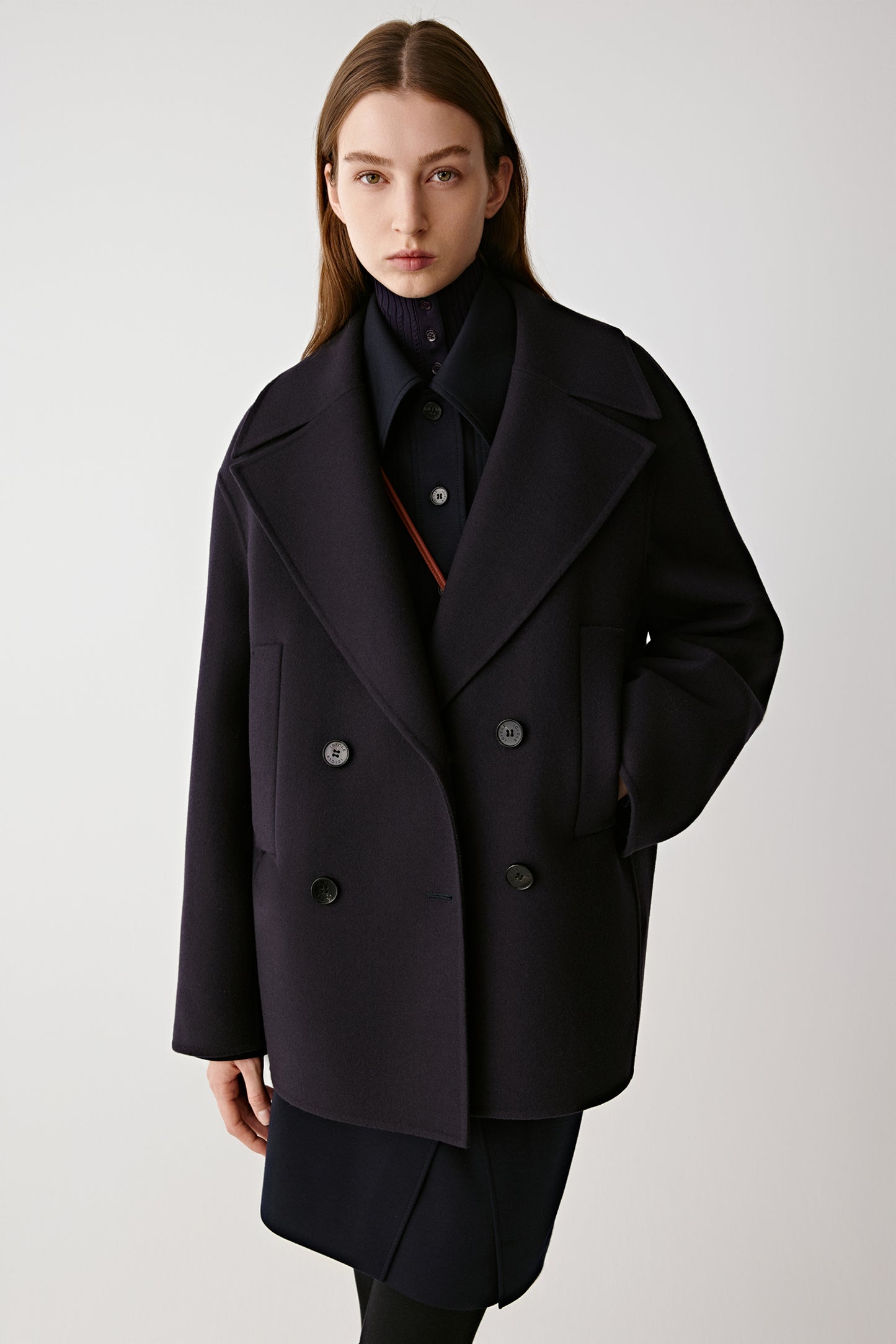 Three-quarter view of the model wearing the peacoat highlighting its wide lapels and patch pockets.