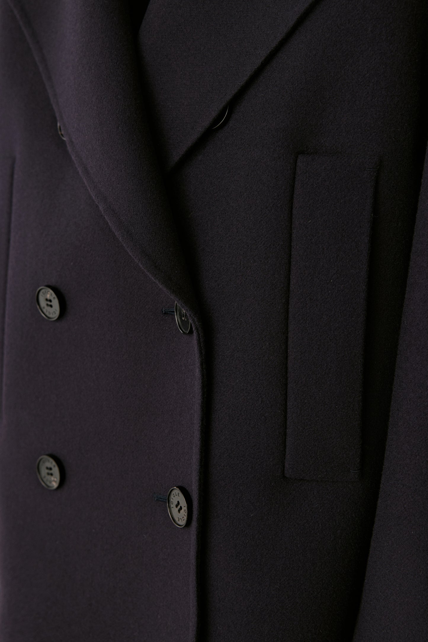Detailed close-up of the gold-tone buttons and fine tailoring on the navy peacoat.