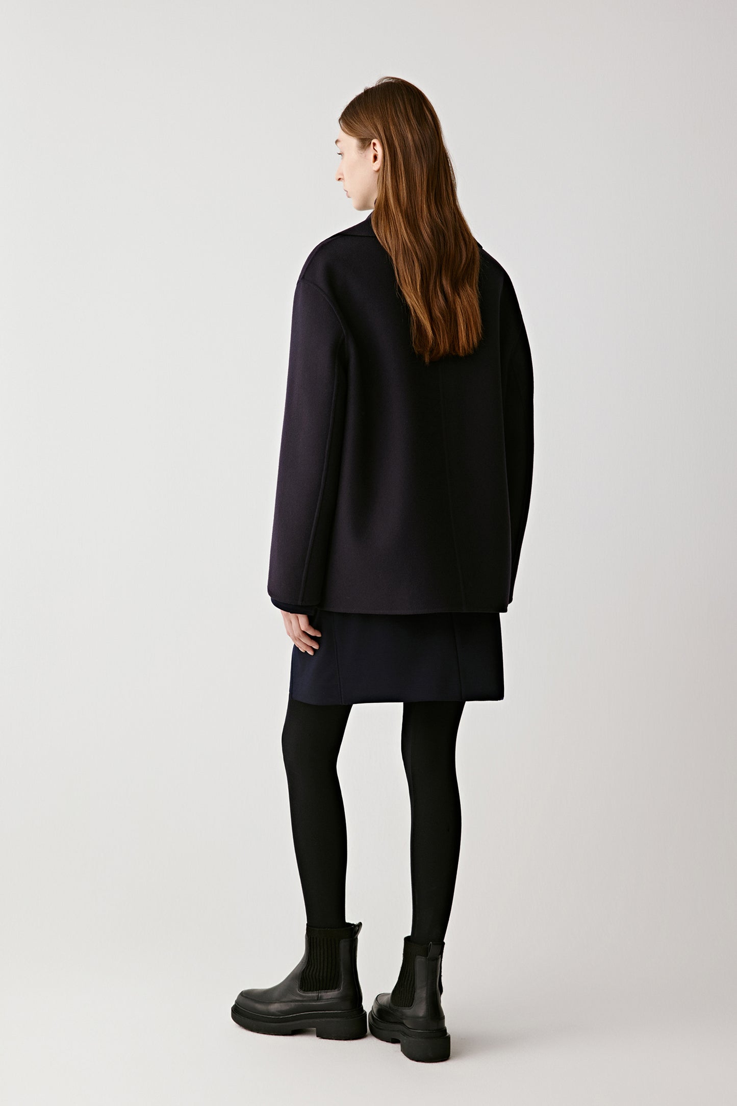 Back view of the navy wool and cashmere peacoat showing its straight cut and structured silhouette.