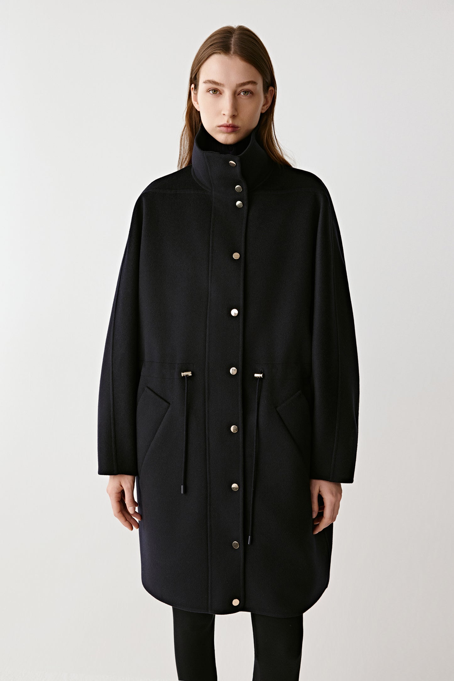 Three-quarter front view of the navy coat emphasizing its tailored design and wide cut.