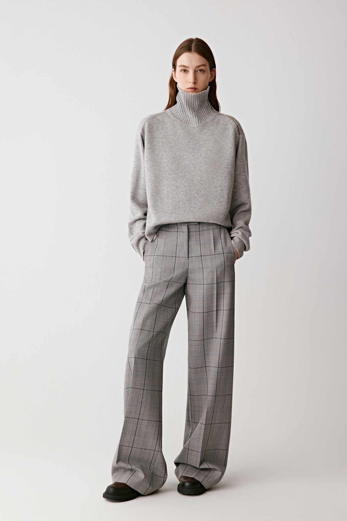 Full-length front view of the model wearing the light grey checked wool trousers with a matching top, showing their wide-leg cut and fluid drape.